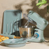 Green stand mixer set with baking tools and bowl, shown on kitchen worktop.