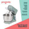 Teal stand mixer kneading bread dough in metal bowl, with loaf, eggshells and ingredients nearby