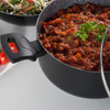 Black saucepan with glass lid showing tomato-based stew and parsley garnish.
