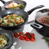 Set of non-stick cookware filled with assorted UK-style dishes on white worktop