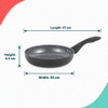 Black non-stick frying pan on induction hob with herb omelette, sliced chilli and spring onion.