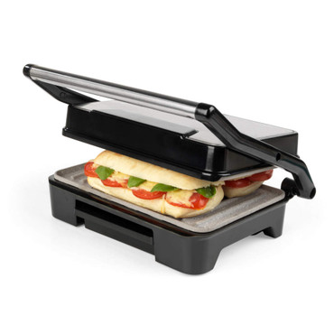 Black panini press toasting sandwich with tomato, cheese, and basil, lid partially closed