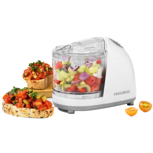 Mini food chopper with clear bowl, filled with fresh chopped vegetables, beside bruschetta slices