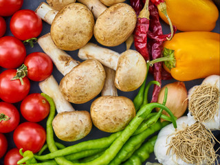 A variety of vibrant vegetables such as carrots, peppers, and tomatoes are artfully arranged around a platter of sautéed wine cap mushrooms, cooked to perfection.