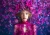 Dramatic botanical portrait of a young woman surrounded by hot pink blossoms, wearing an intricate floral lace dress in vivid magenta.