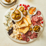 Charcuterie board with assorted olives, antipasti, meat, cheese and toast