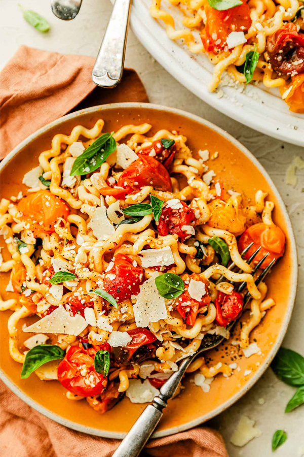 Burst Tomato Pasta with parmesan cheese and basil leaves.