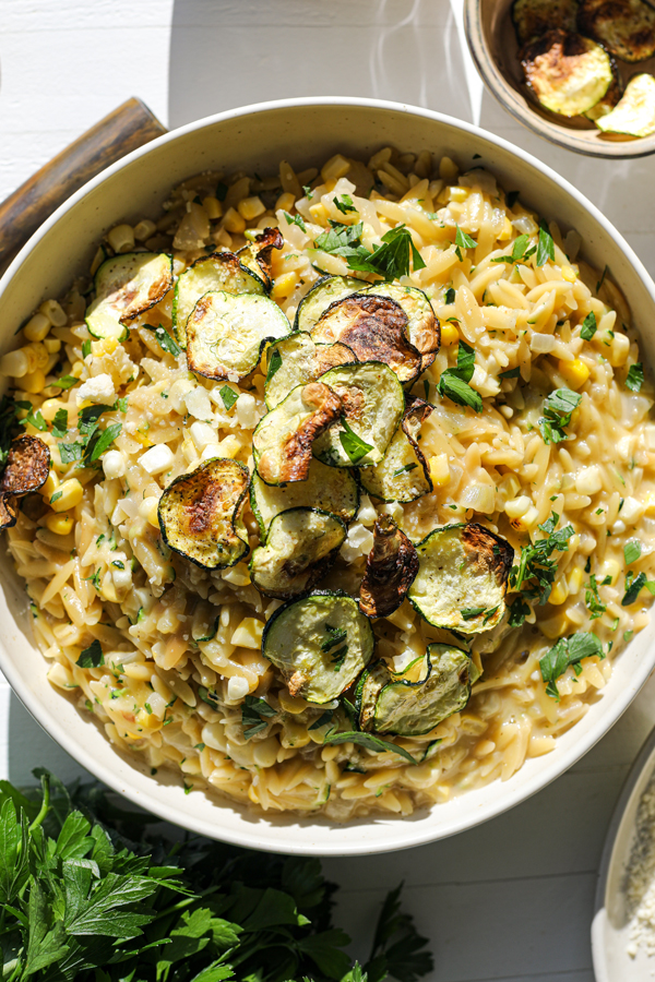 Creamy corn and zucchini orzo, garnished with parsley.