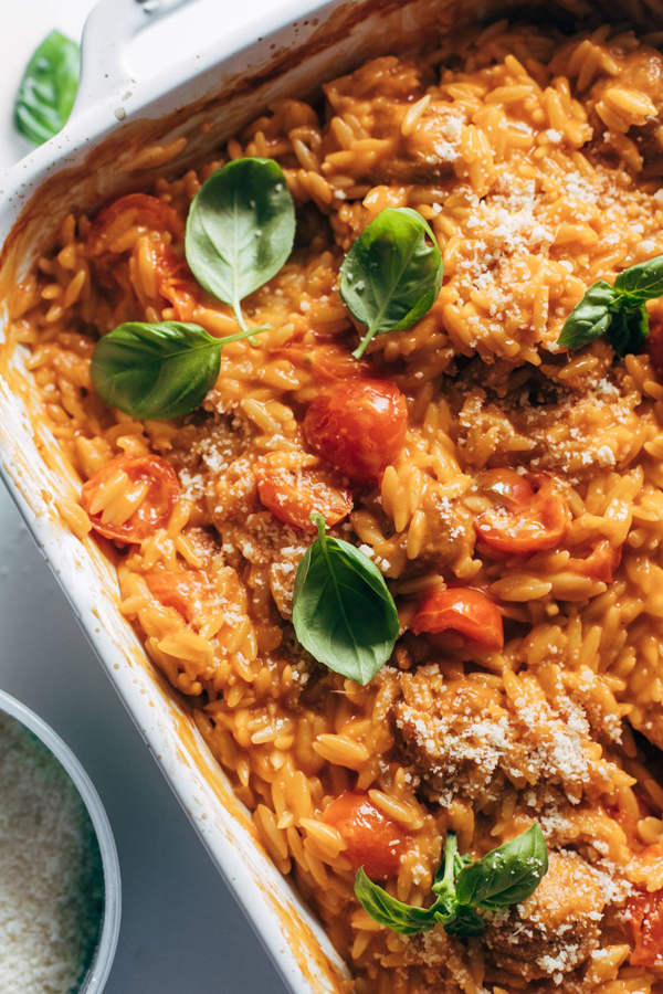 Creamy orzo in a tomato sauce with meatballs, topped with basil and cheese.