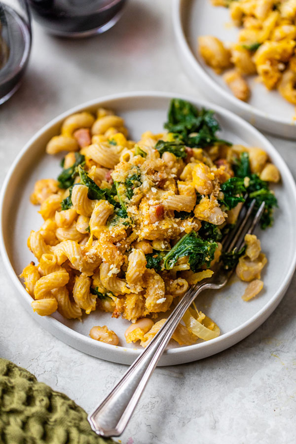 Cavatappi pasta in a pumpkin sauce with kale and pancetta served on a plate