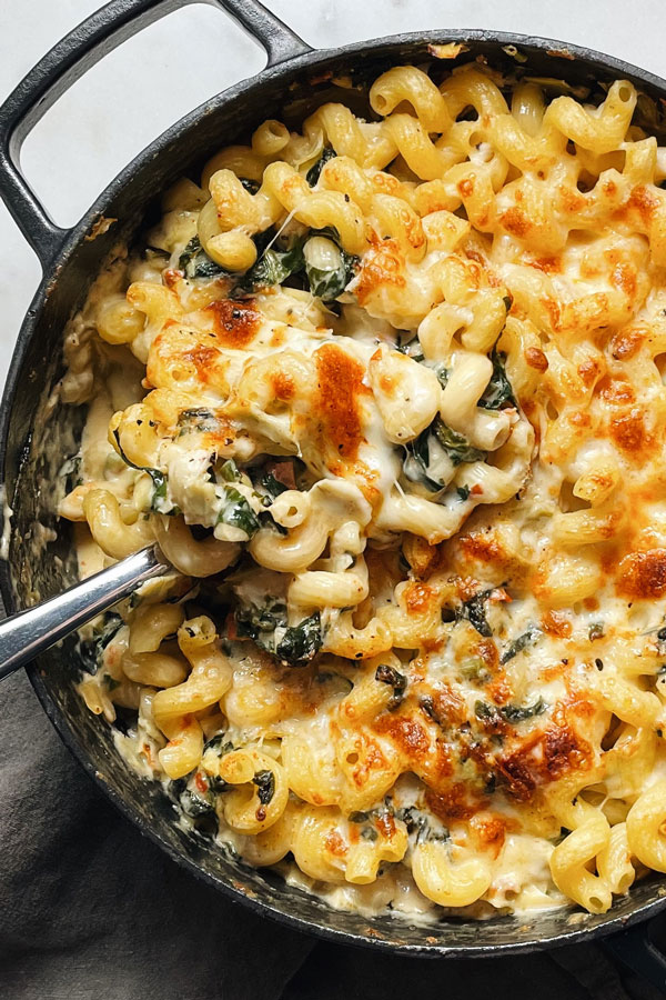 Cavatappi pasta in a creamy cheesy sauce with spinach and artichokes and served in a cast iron pot