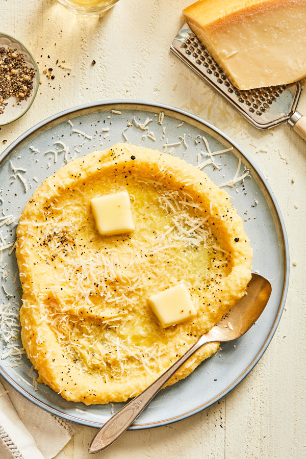 Polenta on plate with butter and shredded parmigiano-reggiano cheese