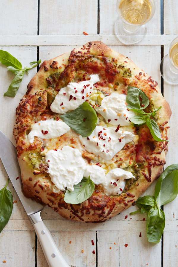 Finished pizza with fresh basil leaves on top and around