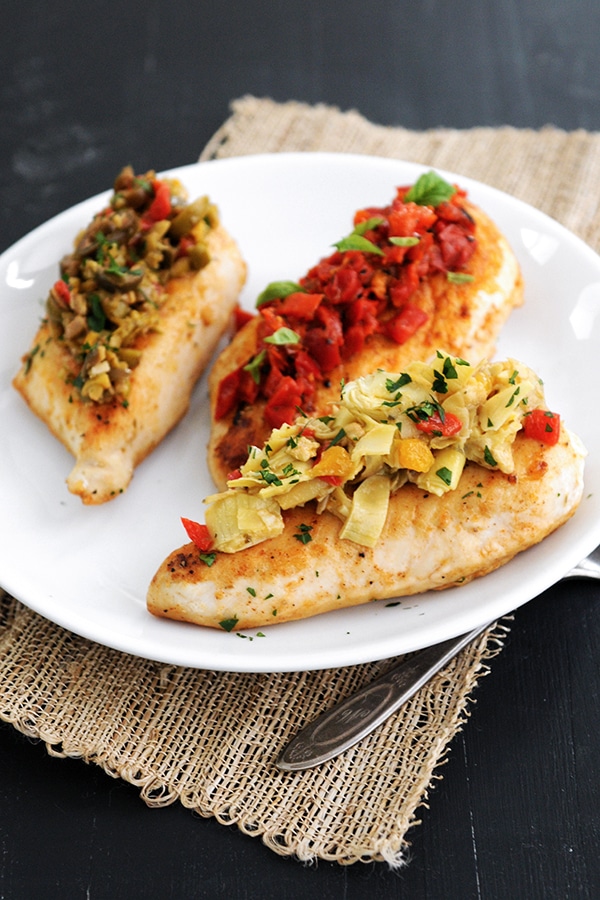 Three pieces of chicken topped with bruschetta and ready to serve. 