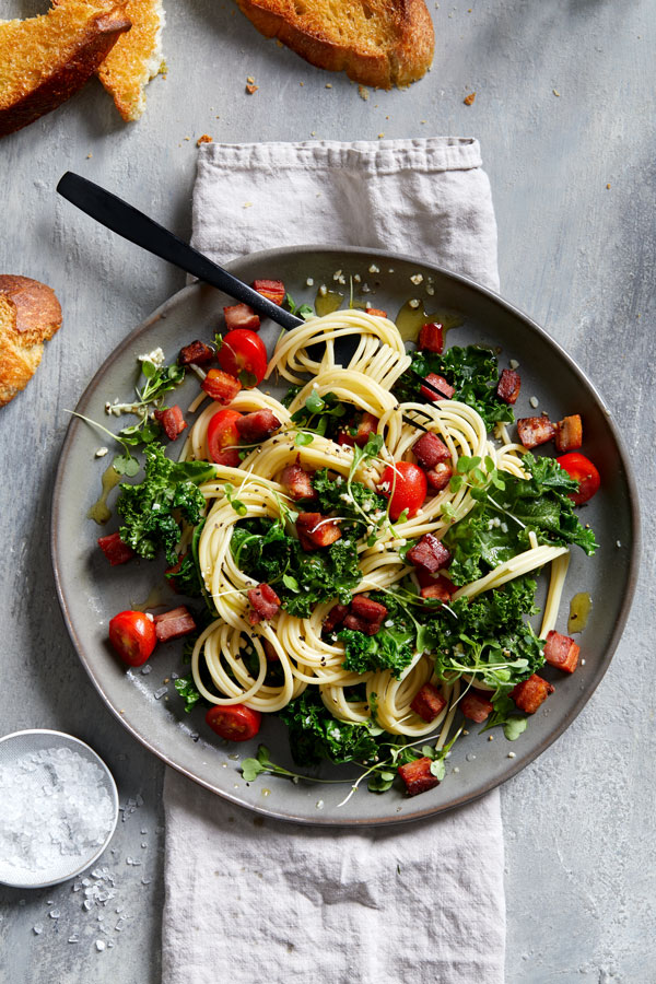 Pasta with tomatoes and kale on a gray plate