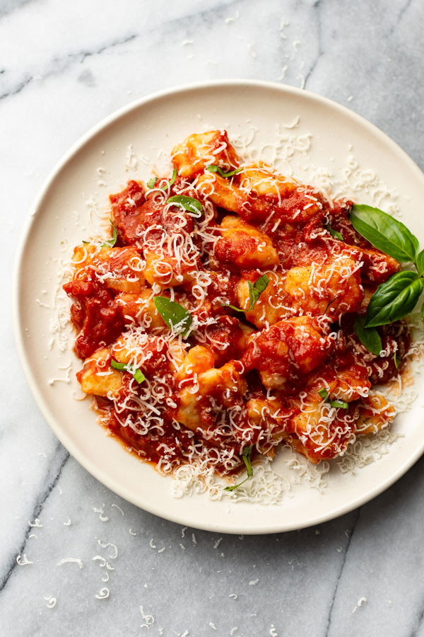 Gnocchi pictured with marinara sauce on a white plate