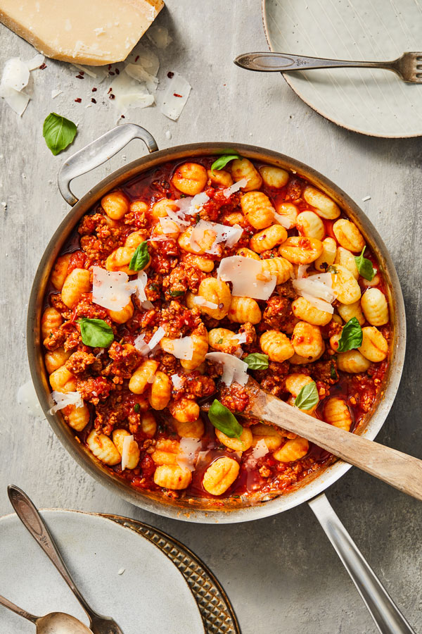 Downshot of gnocchi, sausage, red sauce, basil and shaved cheese in pot