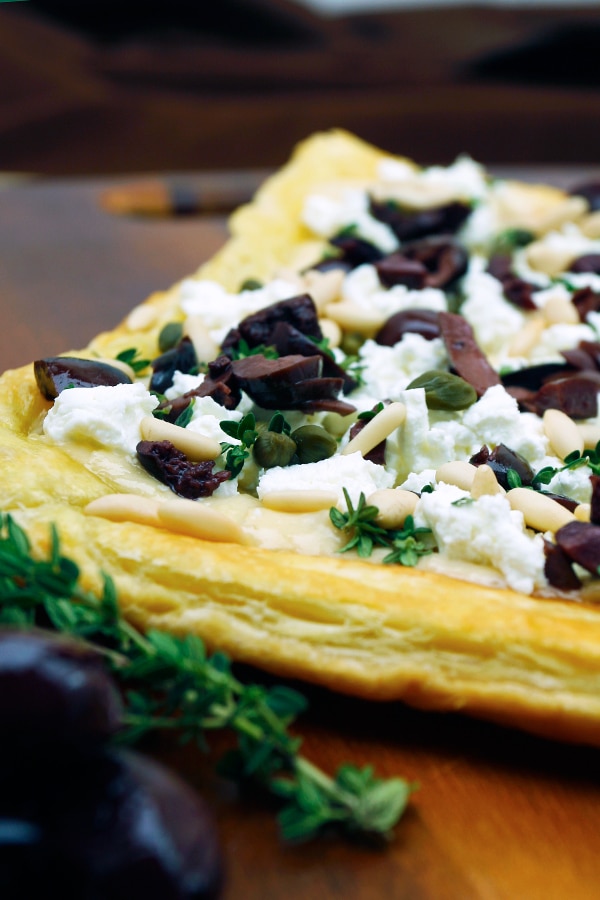 Flakey tart topped with goat cheese and olives 