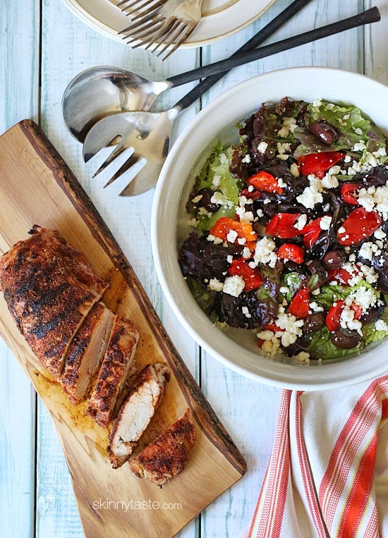 pork tenderloin on a  cutting board next to a fresh salad in a white bowl 