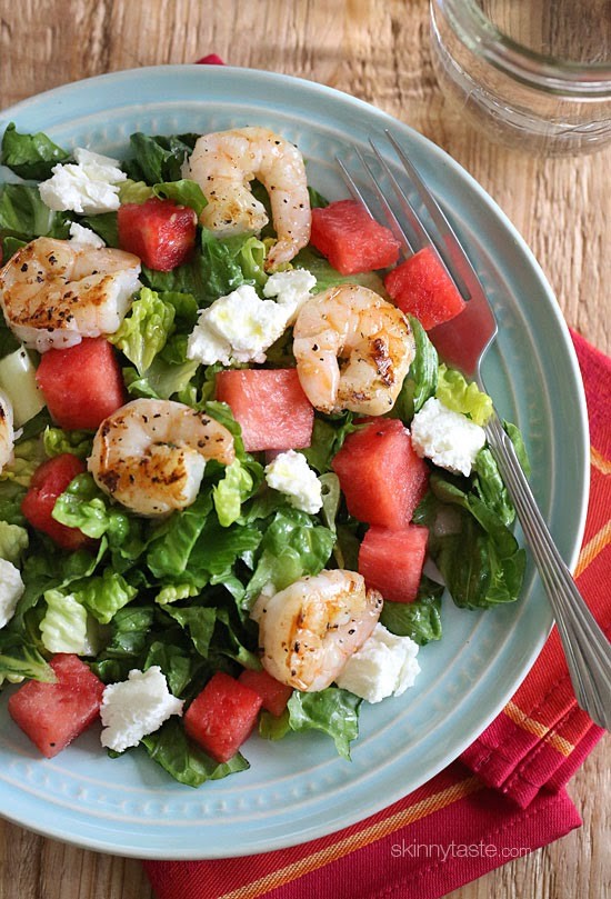 Grilled shrimp and watermelon on top of a bed of lettuce on a blue plate 