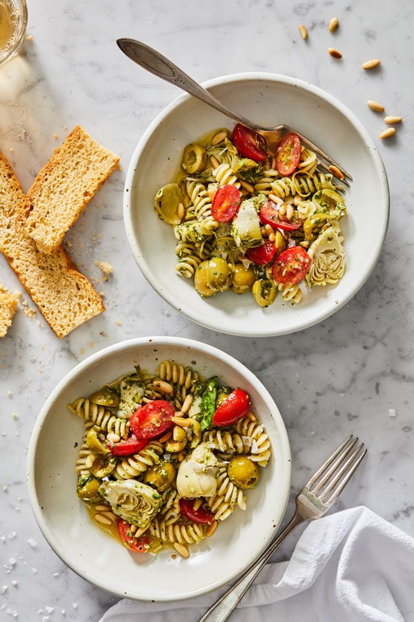 Two bowls of the pesto pasta salad being served with toast. 