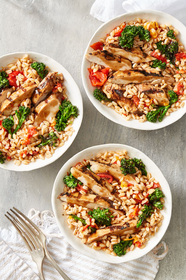 Mediterranean grain bowl with broccoli, chicken, peppers, and farro in white bowl