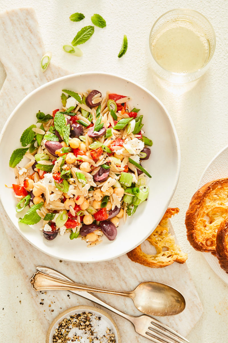 Orzo pictured with greens, olives, and red peppers