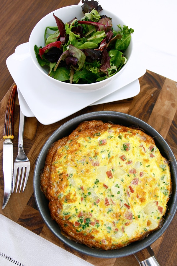 Finished Frittata in pan with a bowl of mixed greens