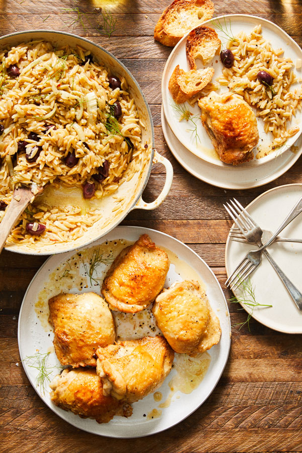 Orzo mixed with olives pictured with a separate plate of cooked chicken