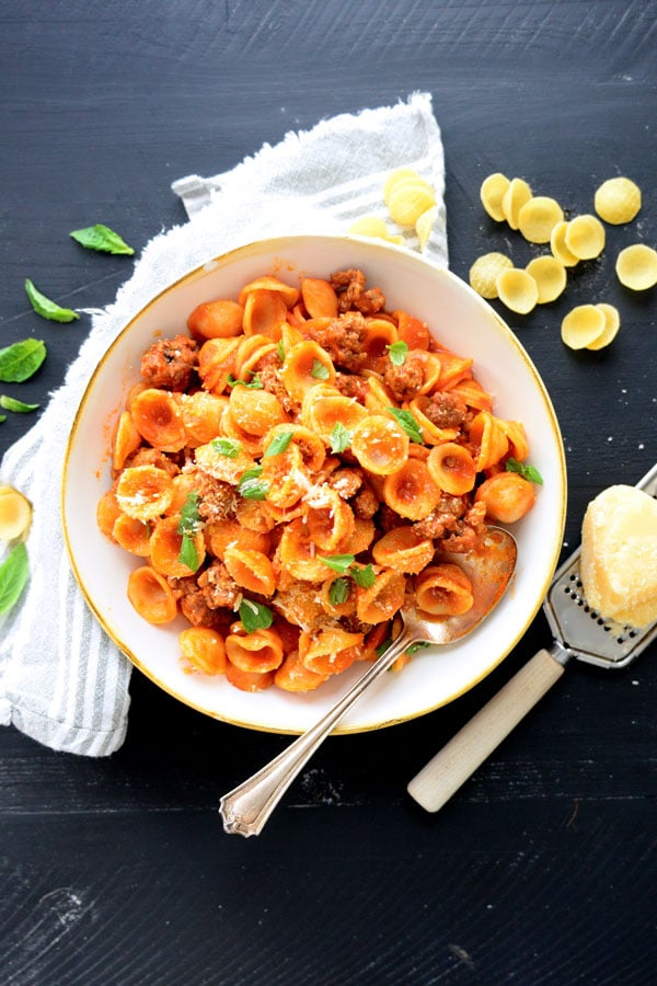 Orecchiette pasta mixed with crumbled sausage in a red sauce and served in a bowl