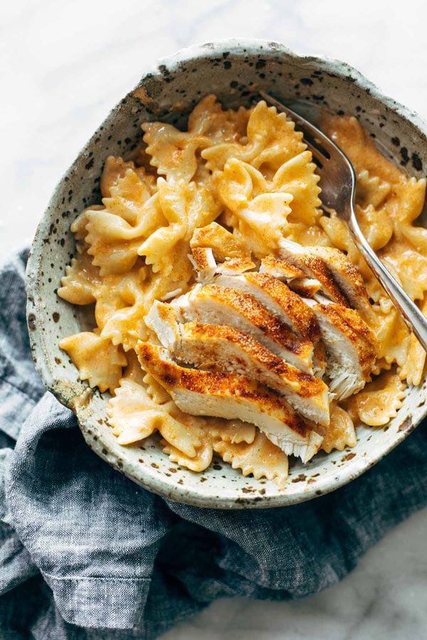 The pasta is served in a bowl and topped with chicken. 