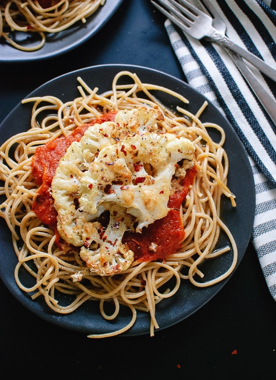 califlower steaks on top of spaghetti on a gray plate 