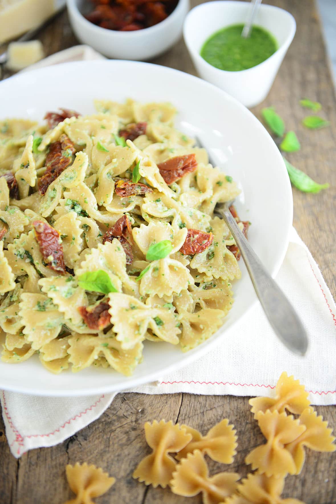 Bowtie pasta with bacon and pesto sauce on a white plate