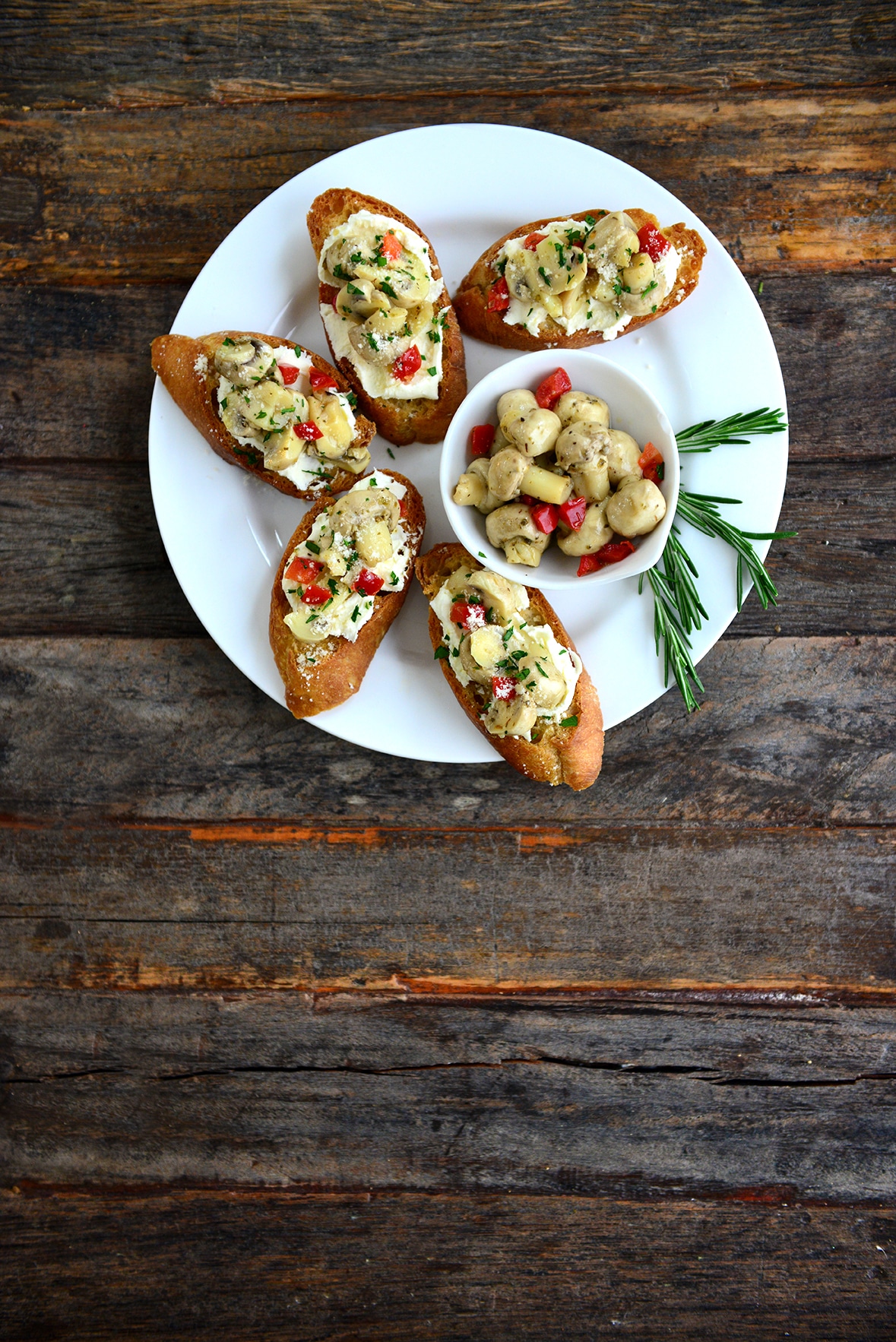 Crostini topped with ricotta and mushrooms on white plate 