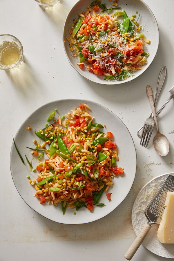 Corn and Tomato Orzo with snap peas on a white plate