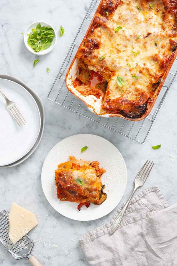 finished lasagna on a cooling rack with one piece on a plate