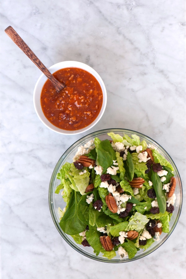 Dressing in container with a bowl of salad