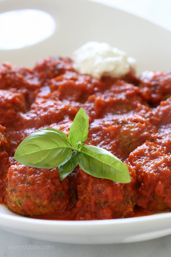 A shallow bowl contains the zucchini "meatballs" garnished with a leaf of basil. 