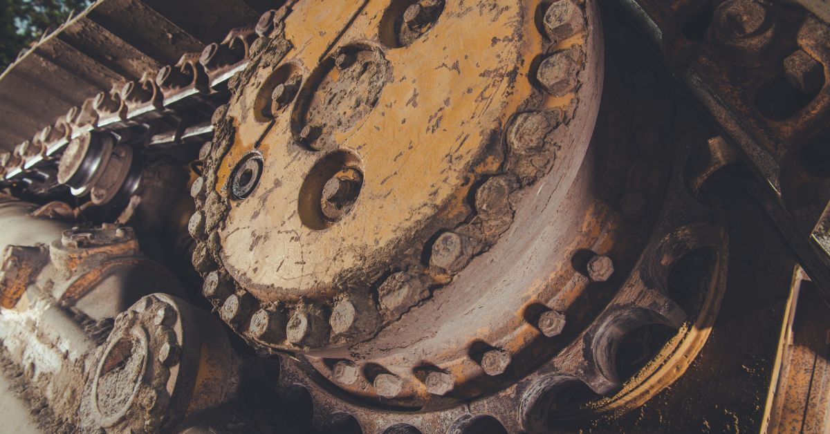 A close-up of the worn-out, dirt-covered components attached to rubber tracks on a piece of large machinery.