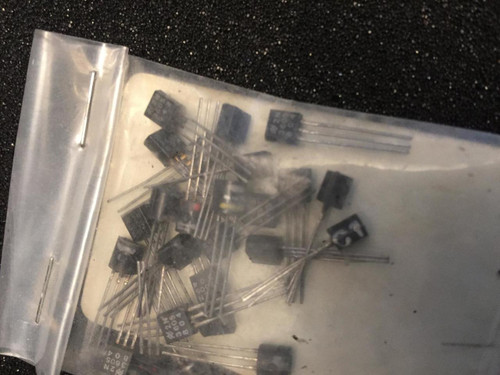 Unsealed static bag containing approximately 25–30 loose TO-92 transistors; leads unbent, bodies intact, markings not legible at this resolution.
