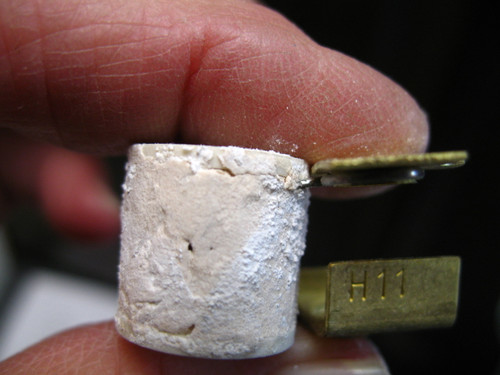 Furnas H11 thermal overload heater element held by fingers, showing the cylindrical body and "H11" stamped on the brass connector.