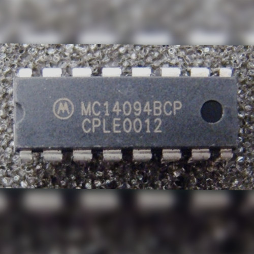 Motorola MC14094BCP 16-pin plastic DIP chip lying on gray surface, marking upright