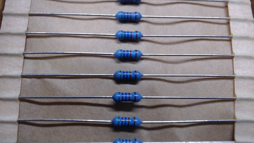 Multiple RG Allen 5K760 Ohm 1% blue resistors with color bands, packaged in rows on tape.