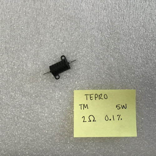 Small black cylindrical resistor with wire leads extending from both ends and mounting tabs visible on the sides, displayed next to a yellow sticky note listing the specifications: "TEPRO TM 5W 2Ω 0.1%.