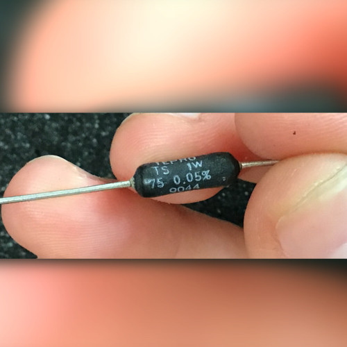 Fingers hold black axial resistor printed TEPRO TS 1W, 75 0.05%, and 9044