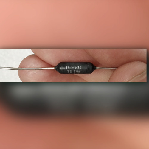 Fingers hold charcoal black axial resistor, body printed TS 1W, 4, and 0.1%