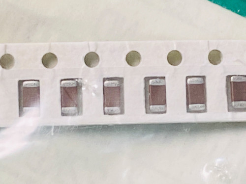 Six mid brown chip capacitors in paper carrier tape, green mat corner top right