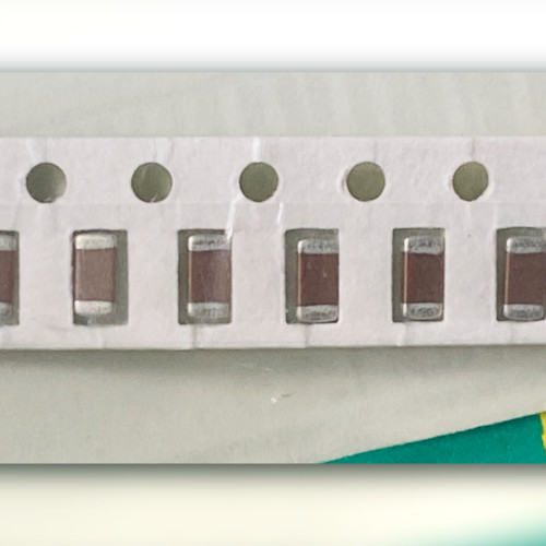 Close view of two brown ceramic chip capacitors with silver-grey end terminations and part of a third