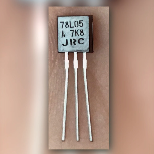 Black TO-92 regulator on a light crinkled surface, face printed 78L05, A 7K8, JRC