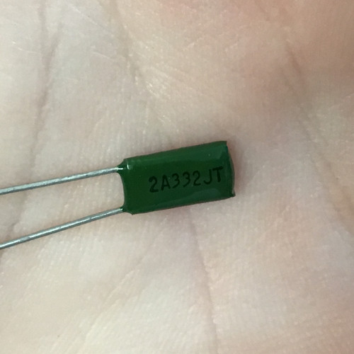 Capacitor body green with "2A332JT" clearly printed. Leads straight, clean, and intact. No visible damage or wear.